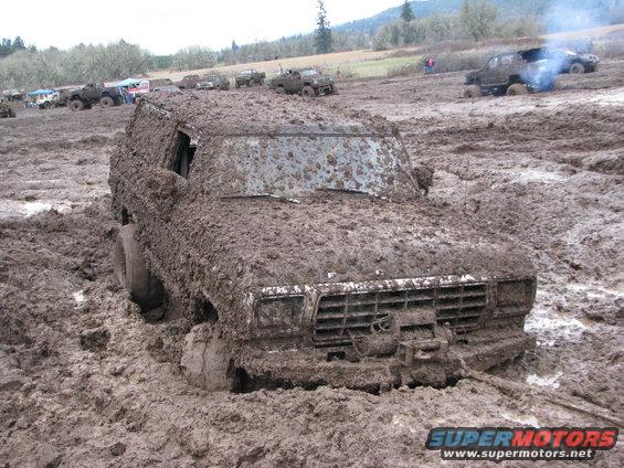 Mud-covered 1978 Ford Bronco stuck in mud, front view with winch