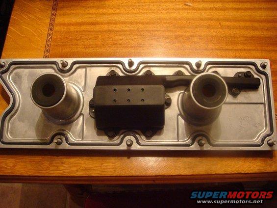 Engine valve cover with two oil fill caps and a black electronic component attached