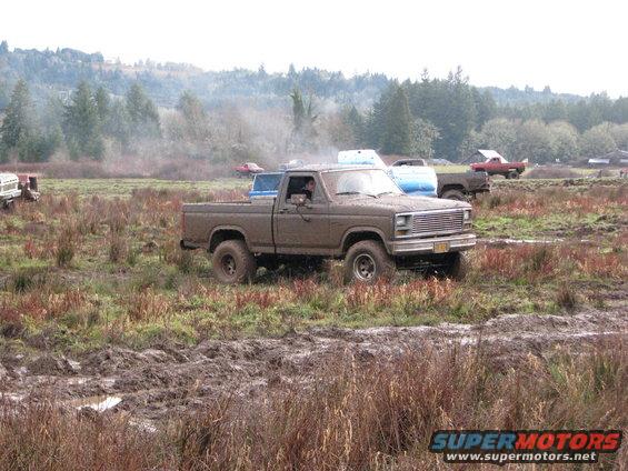 Brown pickup truck stuck in mud, front grille visible