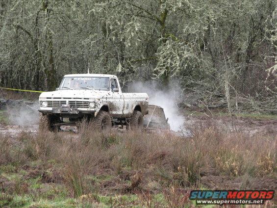 White pickup truck with winch in mud, trees and moss in background