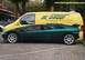 1984 Ford Bronco II - A green sports car is parked beside a yellow van with "DE GROOT" written on its side.