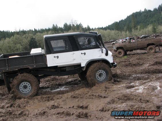 White and black off-road truck with snorkel in mud