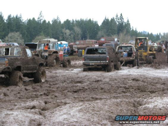 Mud bog scene with trucks and tractor stuck in mud