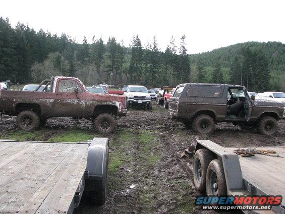 Muddy 1978 Ford Bronco with door open, parked in a muddy field