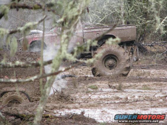 Muddy truck with large tires stuck in a wooded area