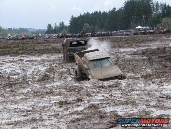 Two trucks stuck deep in mud, one with steam rising
