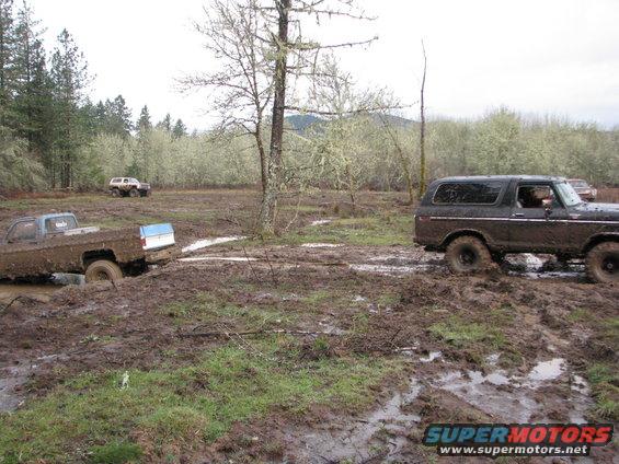 1978 Ford Bronco and a stuck Chevrolet pickup in a muddy field