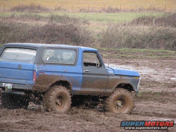 Mud-splattered 1978 Ford Bronco in a muddy field, side view