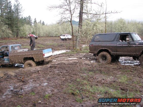 Mud-covered 1978 Ford Bronco in a muddy field, side view