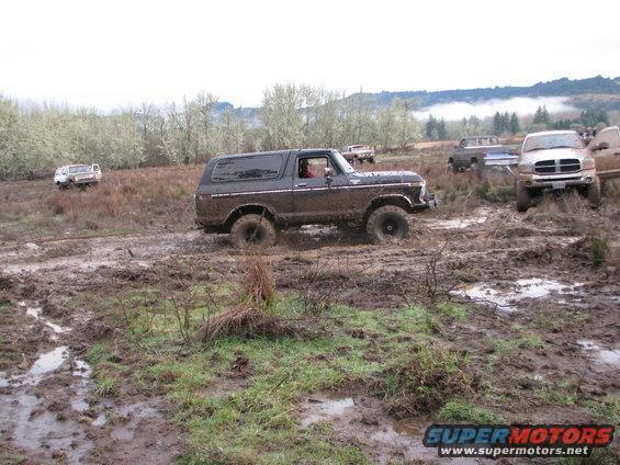 1978 Ford Bronco navigating a muddy off-road course with other vehicles