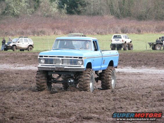 Blue pickup truck with large tires in mud; grille indicates 1973 model