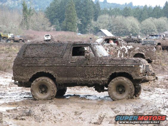Muddy SUV stuck in a muddy field with other vehicles around