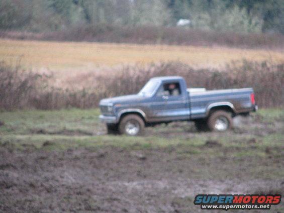 Blue pickup truck driving through mud, 1979 model year
