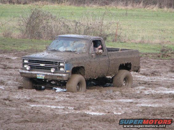 Mud-covered pickup truck stuck in mud, front view