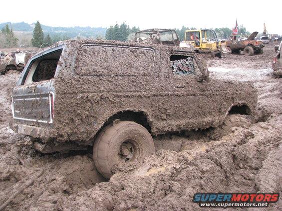 Mud-covered 1978 Ford Bronco stuck in mud, rear quarter view