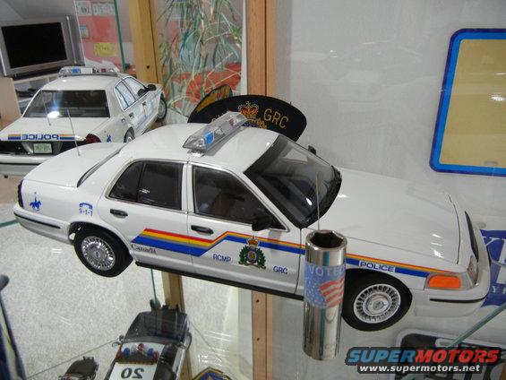 Two white model police cars, one with GRC markings, displayed indoors