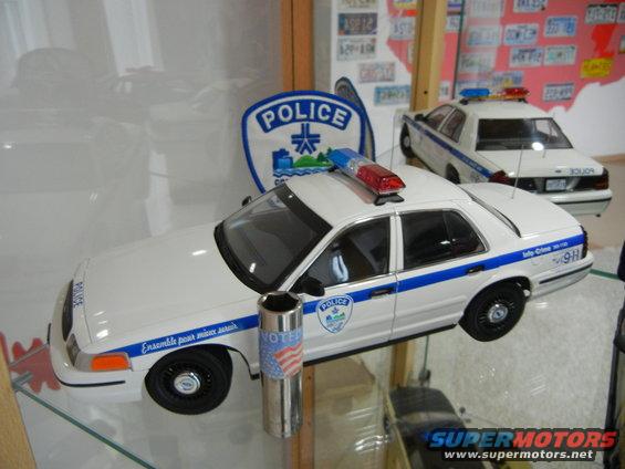 Two white model police cars with blue stripes and light bars. One has 'VOTER' and an American flag sticker
