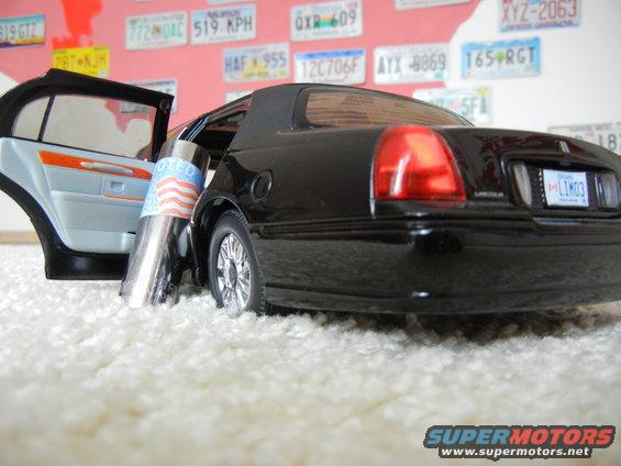 Black 1999 Lincoln Town Car rear view with open door and "Voted" sticker