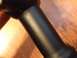 1996 Ford Bronco - A close-up view of a black cylindrical part against a wooden background.