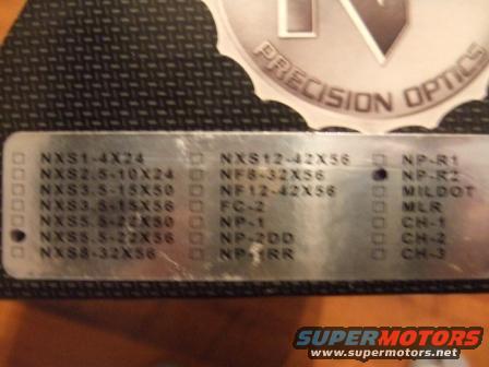 Metal plate with lists of part numbers and model names, including 'PRECISION OPTICS'