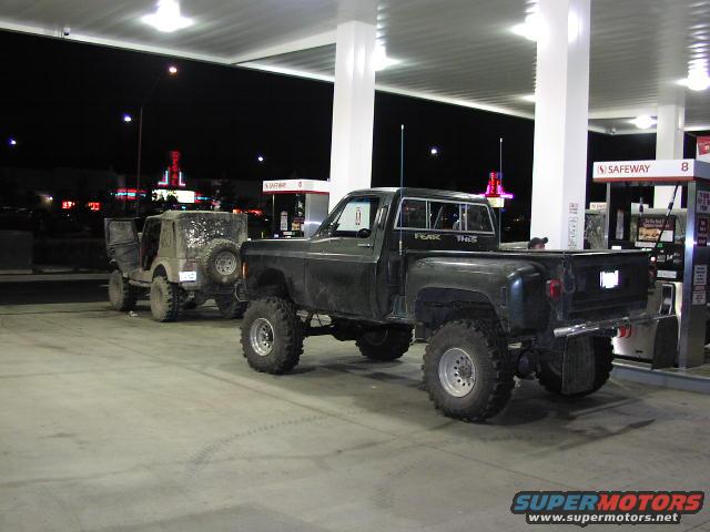 Black lifted pickup truck and Jeep at gas station at night