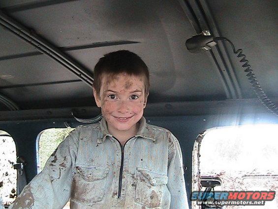 Child with dirt on face and clothes smiles inside a vehicle