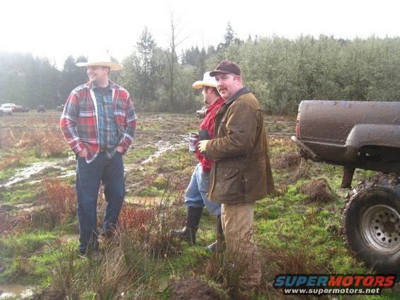 Muddy pickup truck rear and people in a field