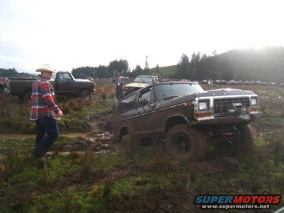 Muddy 1978 Ford Bronco with winch, other trucks in background