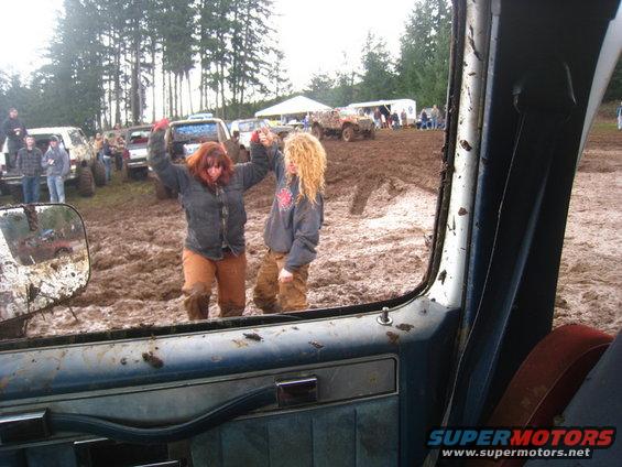 Interior view of a muddy vehicle at a mud bogging event with two women celebrating