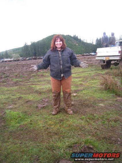 Woman in muddy field with trucks in background