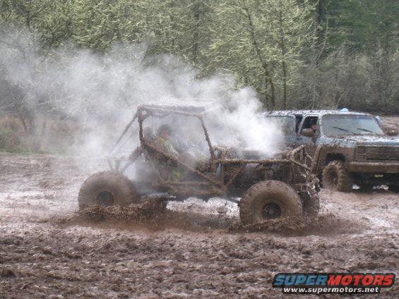 Buggy kicking up mud with a lifted SUV behind it