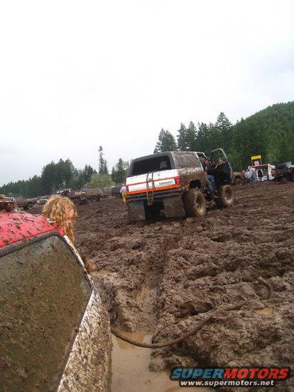 Muddy off-road vehicles stuck in a mire, with people around