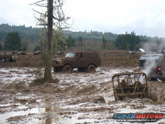 Muddy 1978 Ford Bronco and other off-road vehicles stuck in a muddy field
