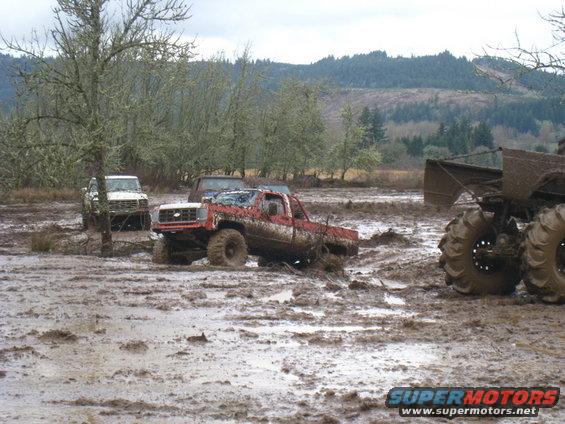 Red pickup truck stuck in mud, 3q-front view