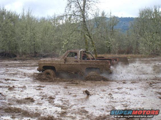 Pickup truck stuck in mud, another vehicle behind it