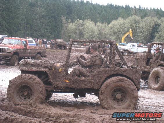 Mud-covered off-road vehicle with driver in a muddy field
