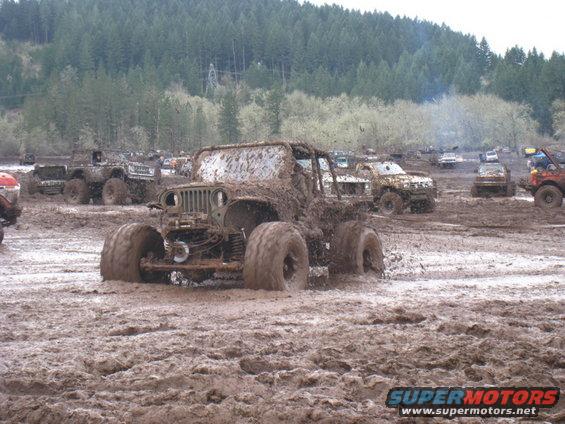 Jeep stuck in mud, other off-road vehicles in background