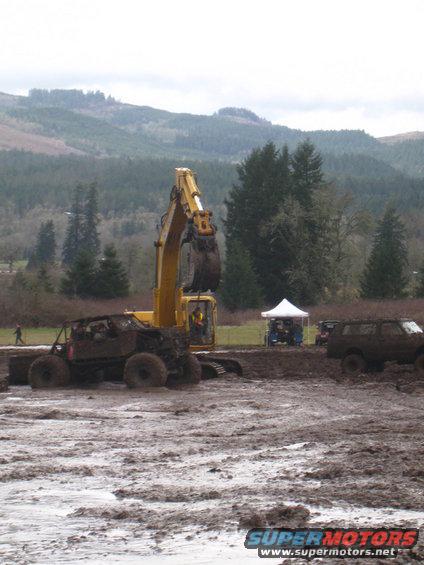 Mud bogging scene with excavator, off-road buggy, and SUV in muddy terrain