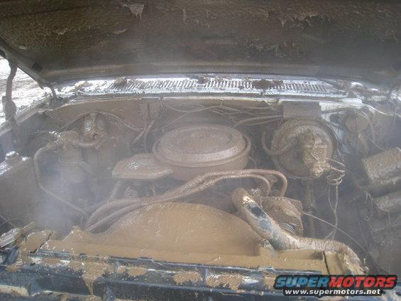 Mud-covered engine bay with hoses and air cleaner visible