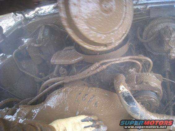 Mud-covered engine bay with visible hoses and air cleaner