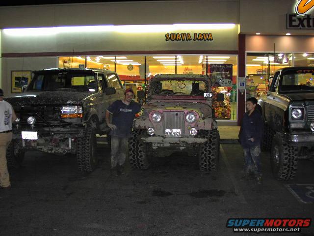 Mud-covered black Ford Bronco from the front, lifted with large tires