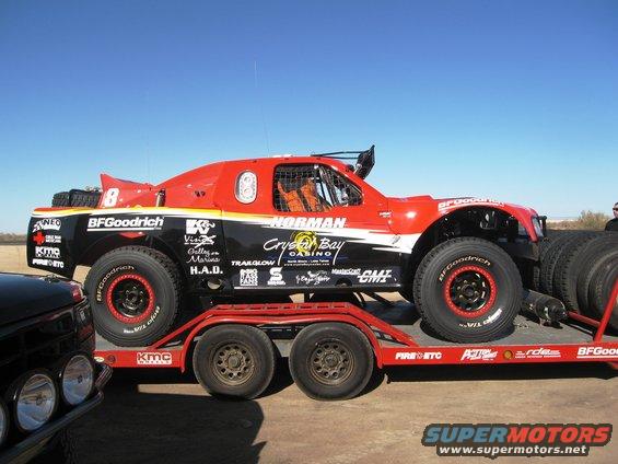 Red off-road racing truck on a trailer, with BFGoodrich tires and various sponsor decals