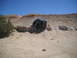 1986 Ford Bronco II - SUV navigates a challenging dirt trail with steep inclines and rocky terrain under a clear blue sky.