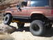 1986 Ford Bronco II - Modified 1986 Ford Bronco II navigating rough terrain with large off-road tires.
