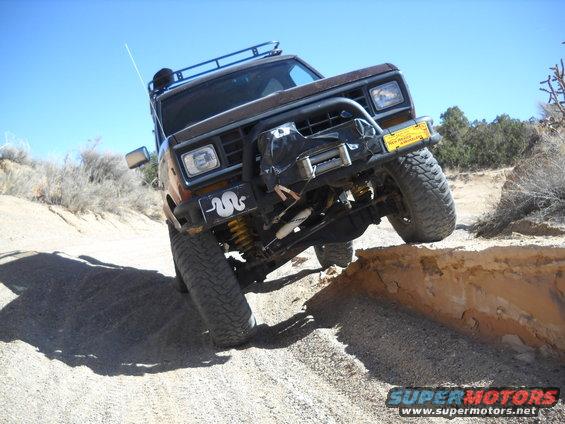 Brown 1986 Ford Bronco II driving off-road, climbing over a dirt ledge