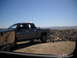 1986 Ford Bronco II - A gray pickup truck is parked on a dirt hill with a vast desert landscape in the background under a clear blue sky.