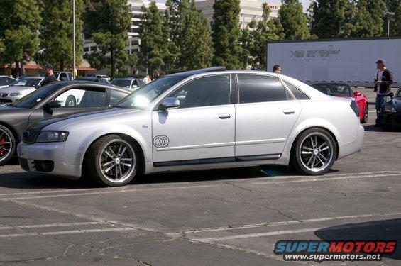 Silver sedan parked in a lot, other cars visible in background