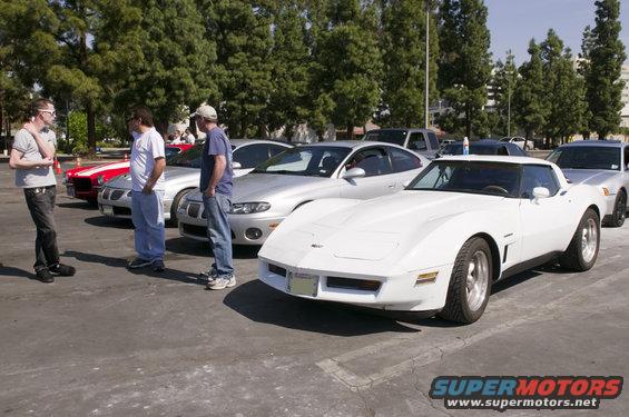 White C3 Corvette parked in a lot with people and other cars