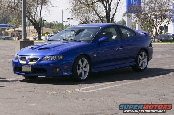 Blue coupe with a prominent grille and hood scoops, parked in a lot