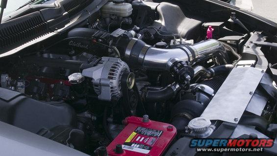 Engine bay with Edelbrock intake, large intercooler piping, and a red battery